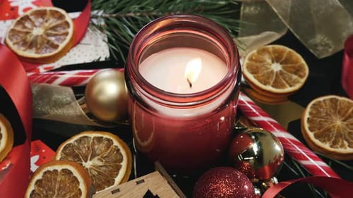Burning Christmas Candle with Festive Ornaments