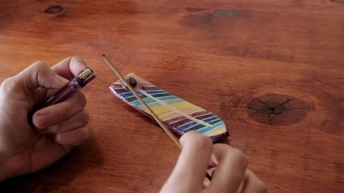 Hand Lighting Incense Stick on Wooden Table