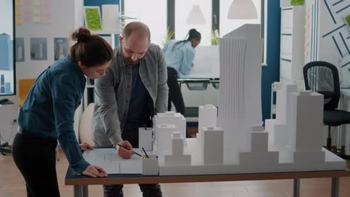 Arbeitskollegen, die Maquette und Baupläne analysieren, planen auf dem Tisch, um an Architektur und Gebäudemodell zu arbeiten