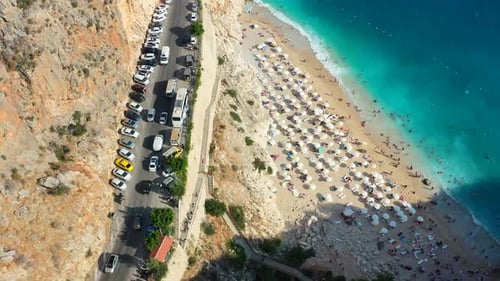 aerial top down view of traffic on a coastal road alongside a cliff with the Mediterranean Sea below
