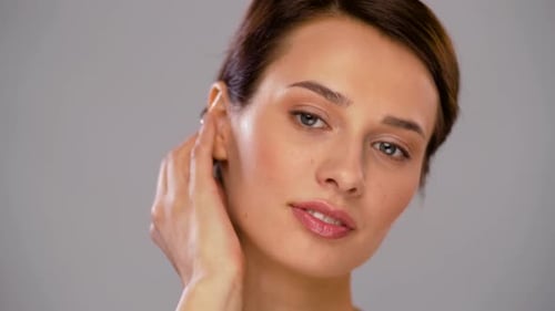 Woman Touches Face and Smiles