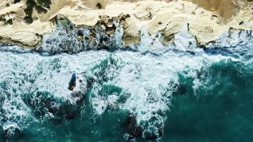 Sea Washes the Rocky Shore Above Aerial Shot Flying Over Coastline Cliffside with Blue Pure Water