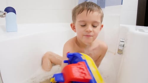 Young Child Playing with Toy Boat in Bathtub