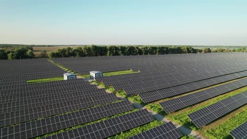 Vue aérienne de la ferme solaire sur le champ vert au coucher du soleil, panneaux solaires en rangée