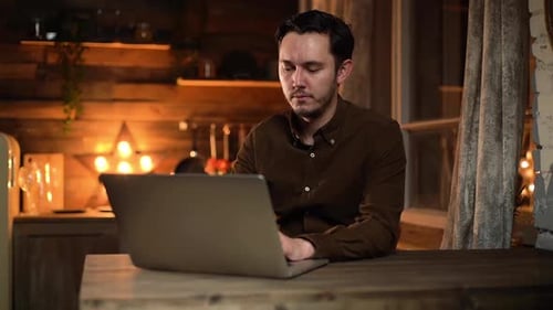 Man working on laptop at wooden desk