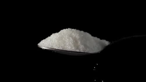 Sugar in a Spoon Closeup on Isolated Black Background
