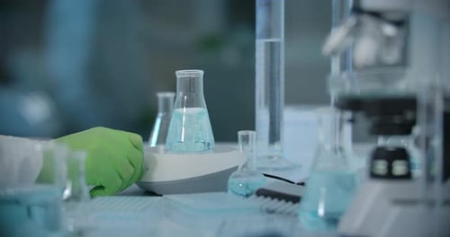 Laboratory Glassware with Blue Liquid and Scientist