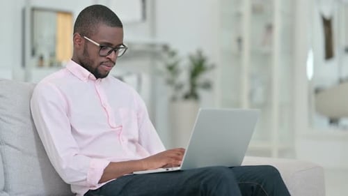 African Man with Laptop Looking at the Camera at Home
