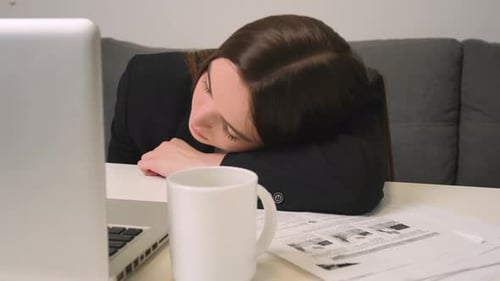 Müde junge Frau arbeitet im Home Office am Laptop