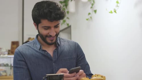 Bel homme utilisant un téléphone portable dans un café.