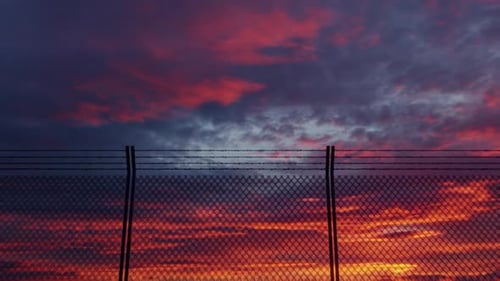 Barbed Wire Security Fence Against a Dramatic Sunset Sky