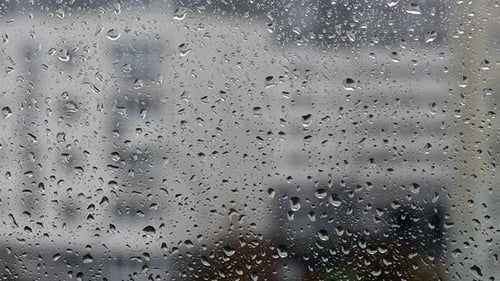 Fensterglas bei Regentropfen. Tropfen laufen das Glas hinunter.