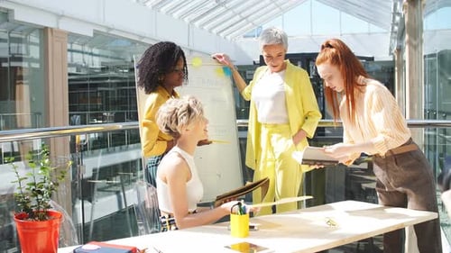 Women Collaborate on Whiteboard in Bright Office