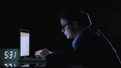 Mujer de negocios en traje preparando informe a última hora de la noche antes de la fecha límite,