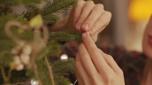 Woman Decorates Christmas Tree with Ornaments and Lights