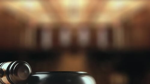 Gavel Strikes Sounding Block on Wooden Table