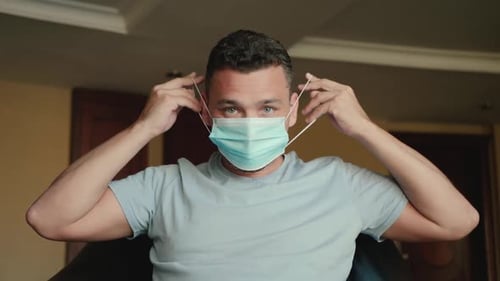 Man Putting on Surgical Mask Indoors