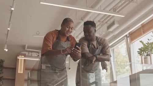 Happy Employees Using Phone in Modern Cafe