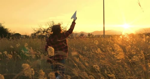 Girl Runs Through Field With Paper Airplane Sunset