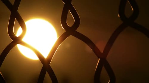 Sun Shining Through Chain Link Fence at Sunset