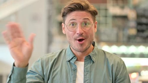 Porträt eines fröhlichen Mannes mittleren Alters, der in die Kamera winkt