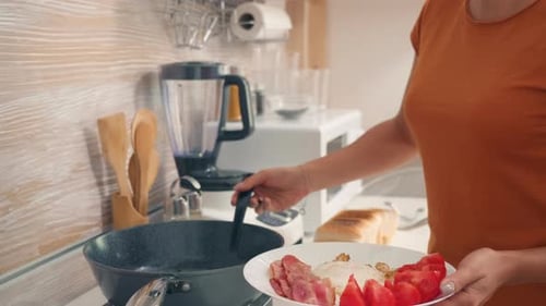 Woman Preparing Fried Egg, Bacon and Tomatoes