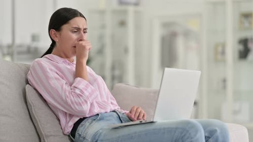 Young Woman Coughing While Using Laptop at Home