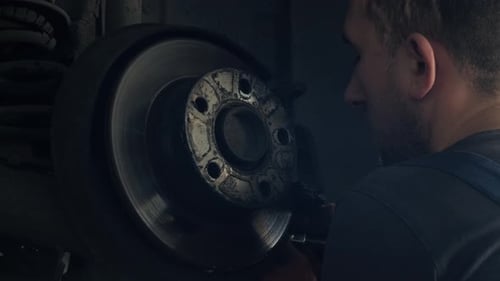 car mechanic replacing car wheel brake shoes of lifted automobile at repair service station
