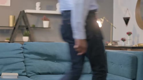 Man Sits Relaxing on Couch Indoors