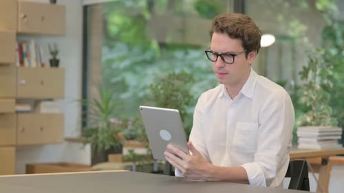 Young Man Using Tablet While Sitting in Modern Office