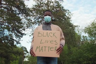 African-American Man in Face Mask Protesting with BLM Sign