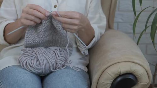 Woman knitting with yarn indoors in daytime
