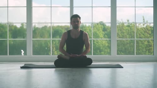 человек медитирует, сидя на полу в светлой комнате