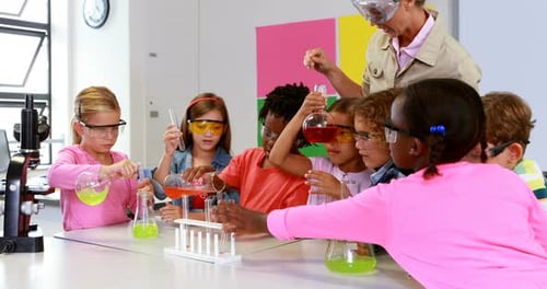 School teacher assisting school kids in chemical experiment in laboratory