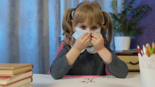 Sad Child Girl Pupil in Medical Mask Doing School Homework at Home Video Call By Webcam on Internet