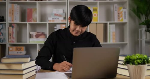 Young Adult Writing and Crumpling Paper at Desk
