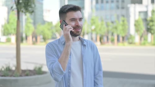 Young Adult Talking on a Mobile Phone Outdoors