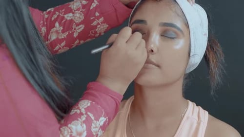 Close up of make up artist putting eye shadow with make up brush on woman's eyes