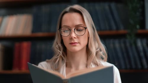 Confident Woman Reading Paper Text Book Turning Page at Library Interior with Bookshelves Closeup