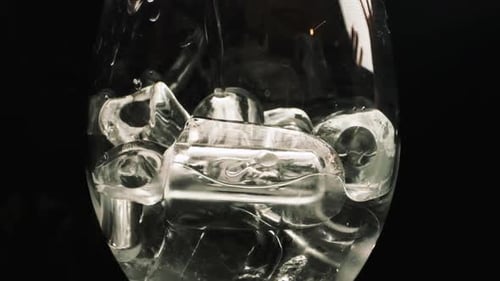 Pouring Liquid Over Ice Cubes in Glass