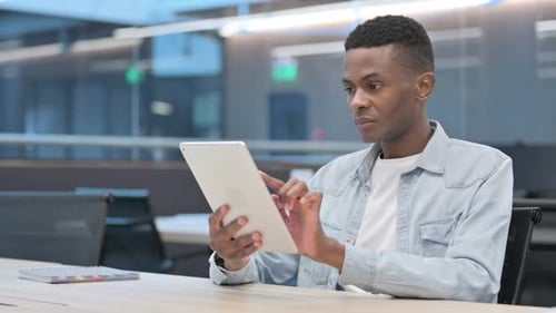 Attractive African Man using Tablet in Office