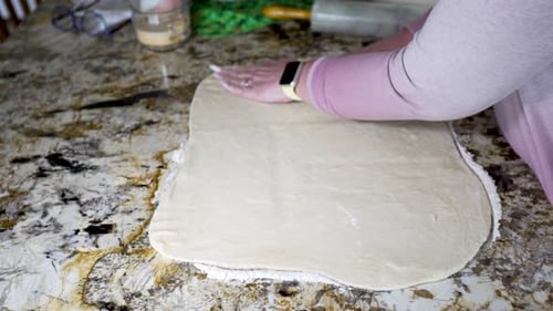 Die Seiten des ausgerollten Teigs quadrieren, um Zimtschnecken herzustellen - isolierte Seitenansicht
