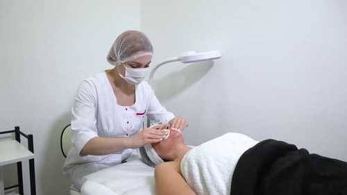 Beautician Using Cotton Pads for Cleansing Face of Woman