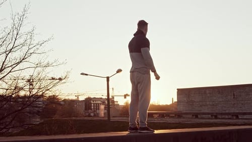 Man Stands on Rooftop at Sunset, City View