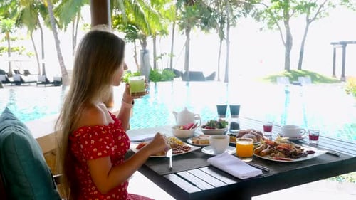 Young Female Tourist Drink Fresh Avocado Juice on Breakfast at Poolside Outdoors Restaurant in