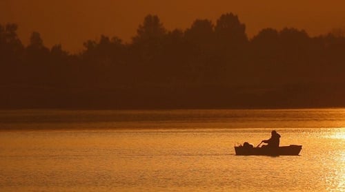 Silhouette of Fisherman in Boat During Golden Sunset