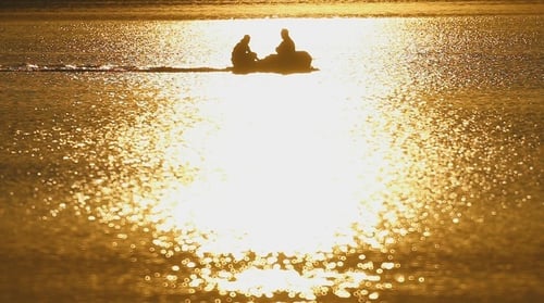 Silhouetted Boat Glides on Glistening Water at Sunset