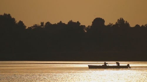 People Rowing Boat on Lake at Sunset