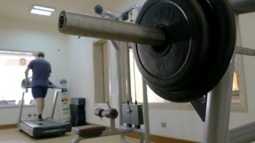 Sportler legt Scheibengewicht auf die Langhantel