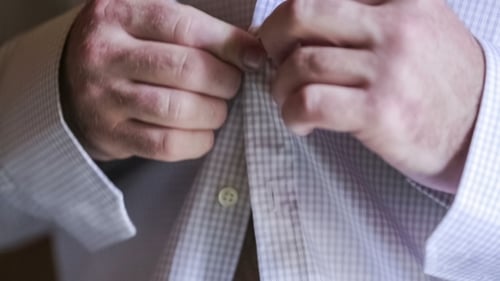 Man Buttoning Light Blue Dress Shirt Close Up